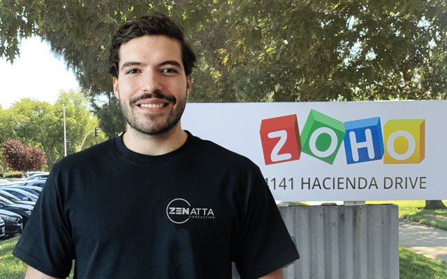 Hector Gonzalez, a developer at Zenatta Consulting standing in front of a Zoho sign under a tree
